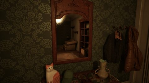 Dorm room corner with damask wallpaper, a mirror, coats and a porcelain cat figurine